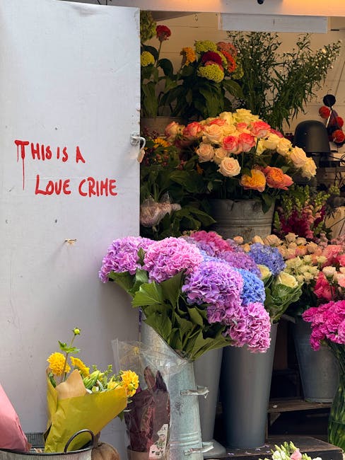 A display of fresh floral arrangements at a flower shop, featuring a prominent bouquet of pink and purple hydrangeas in a transparent wrapping, placed on a table among other vibrant flowers including 